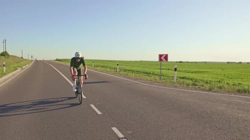 Cyclist Rides Down Open Road on Sunny Day