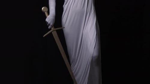 A Woman is Standing on Pedestal As a Marble Statue of Themis