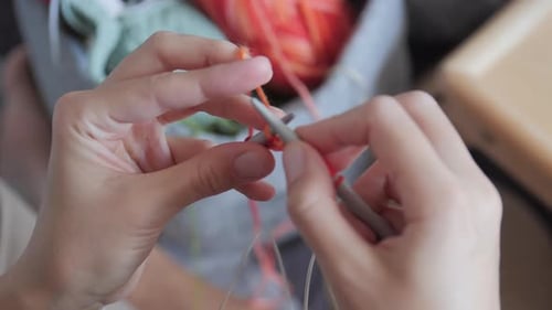 Close Up of Hands Knitting with Orange Yarn