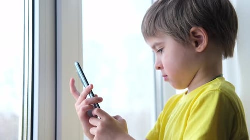 Child Using Smartphone Indoors by the Window