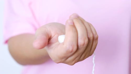 Medizinischer Tampon für Frauen, die ihr Bewusstsein für weibliche Hygiene vor zartem rosafarbenem Hintergrund zum Ausdruck bringen