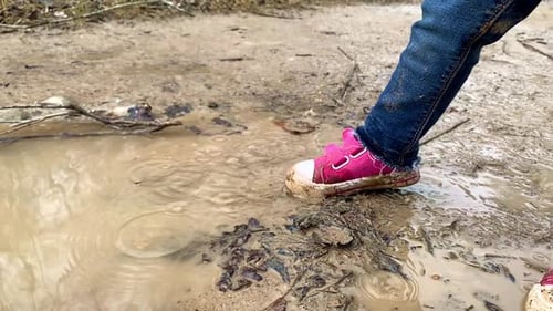 Child Splashing in Muddy Puddle in Rural Area