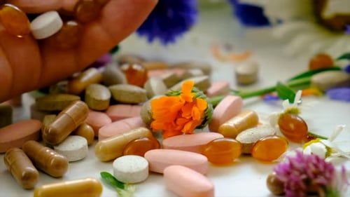 Pills and Capsules with Flowers Close Up