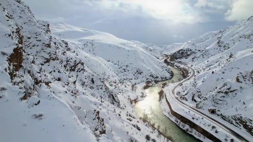 Verschneiter Canyon mit Fluss und Eisenbahntunnel