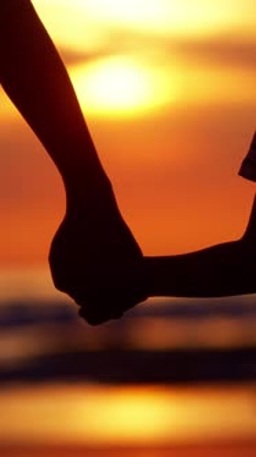 Child and Parent Holding Hands at Sunset Beach