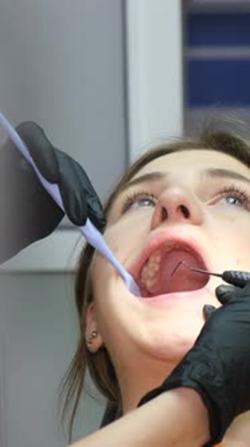 Der Prozess der Behandlung der Zähne einer jungen Frau mit Hilfe von Zahninstrumenten Vertikal