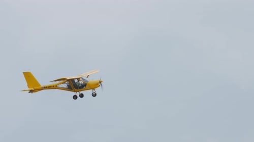 Yellow Airplane Flying in Overcast Sky