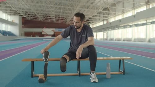 Amputee Removing Prosthetic Leg on Bench Indoors
