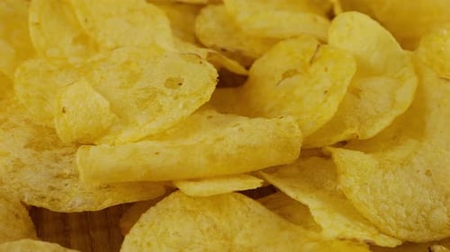 Potato chips rotating close up on a wooden board.