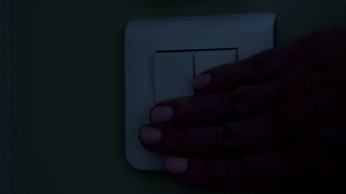 Mulher pressiona os botões do interruptor branco para desligar a luz