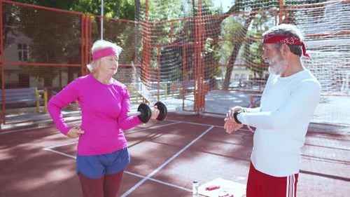 Seniors working out with dumbbell on sports court