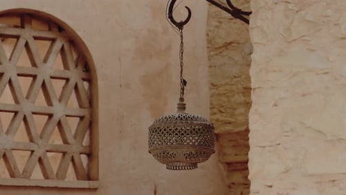 Ornate Metal Lantern Hangs on Beige Wall Outside Moroccan Building