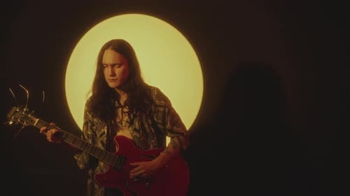 Young Indie Rock Musician Playing Guitar in Spotlight