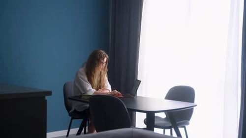 Woman Working with Laptop and Notebook at Table