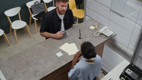 Client Handing Passport and Cash to Female Bank Teller in Office, High Angle