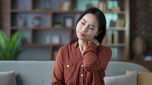 Young Woman Massages Sore Neck Indoors