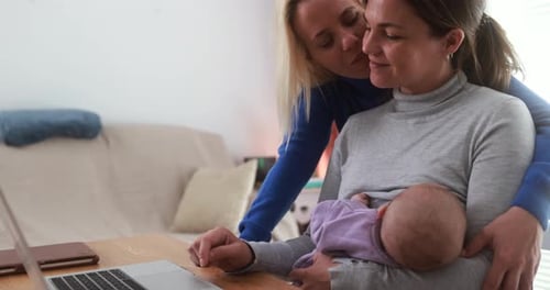 Loving Couple with Baby Using Laptop At Home