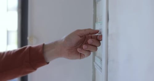 Man Check and Turn Off Circuit Breakers in Electrical Fuse Box at House