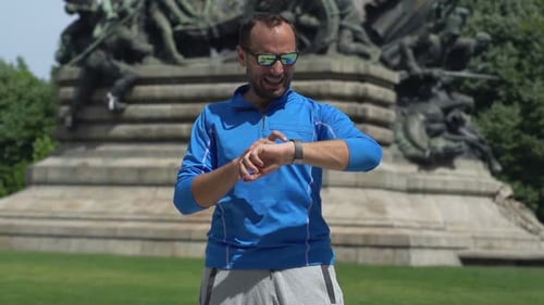 Man Checking Pulse on Smartwatch After Jogging in City Park Active