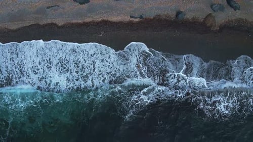 Top Aerial Drone View of Waves Crashing on Grey Stones Coastline
