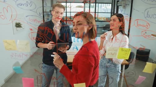 Team Brainstorming Writing on Glass Wall in Office