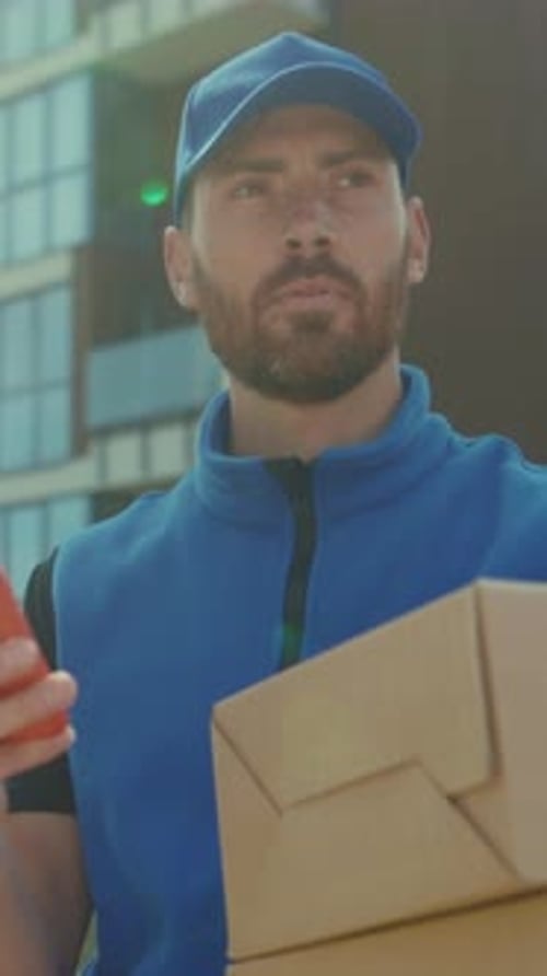 Delivery Man Using Phone While Holding Cardboard Boxes