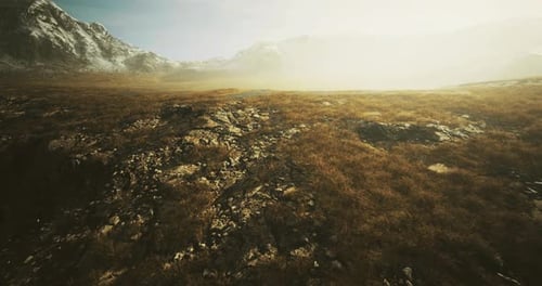 Vast Mountain Landscape Under Soft Sunlight with Rocky Terrain and Grass