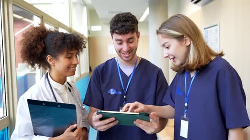 Medical Team Collaboration Analyzing Patient Data on Tablet in Hospital Corridor