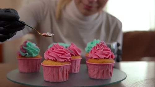 Blonde Woman Decorating Frosted Cupcakes with Sprinkles
