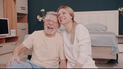 Senior Man and Young Woman Laughing Together Indoors