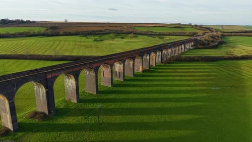 Viaduto ferroviário histórico que se estende por uma paisagem campestre exuberante sob a luz do sol da tarde Histórico