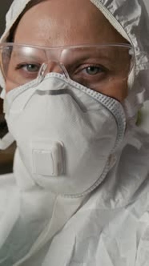 Woman in Protective Wear, Goggles and Respirator Looking at Camera