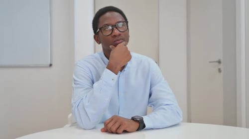 Man Thinking While Sitting at Desk Indoors