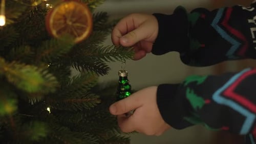 Child Decorates Christmas Tree with Ornaments