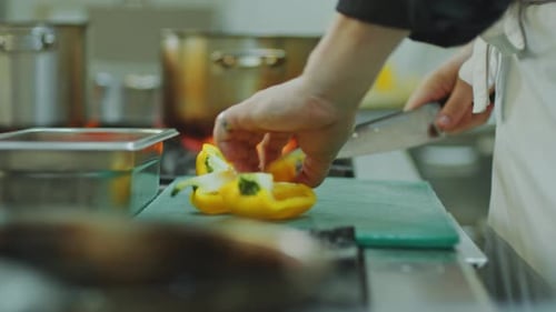 Restaurant Chef Cutting Fresh Bell Pepper at Kitchen Table