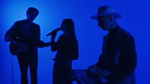 Silhouettes of Glam Rock Trio Performing Music in Blue Neon Lit Studio
