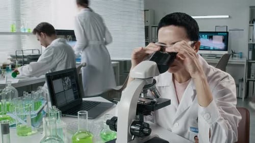 Scientists working in laboratory with microscope and laptop
