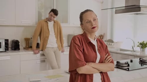 Woman Thinking in Kitchen with Man in Background