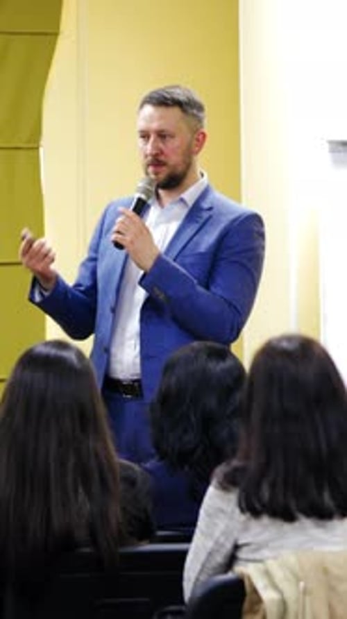 Rear view of audience at conference. Group of people with business trainer at seminar Vertical video