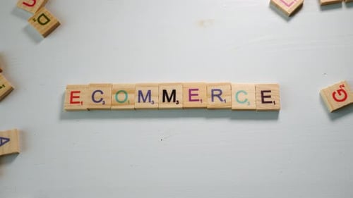 The word Ecommerce spelled with wooden tiles letters. White background. Dramatic light. Flat plane