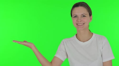 Pointing Young Woman Showing Copyspace on Green Background