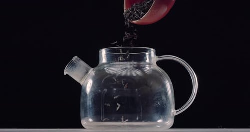 Tea Leaves Falling into Glass Teapot