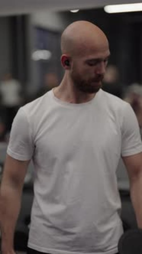 Man Lifting Dumbbells Exercising Biceps in the Gym