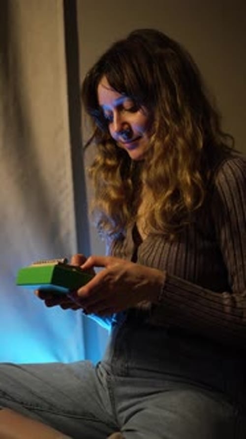 Female Musician Performing Traditional Kalimba Sitting in Soft Blue Lighting Creating Melodic Sounds