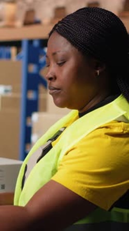 Woman Wearing Vest Stands in Warehouse