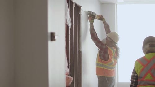 Of Man Cutting Through Partition Wall in Empty Office Space