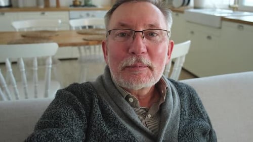 Senior Man Waving at Camera in a House