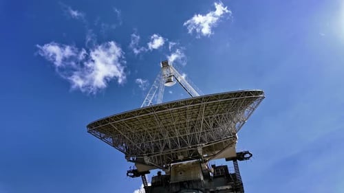 Giant radio telescope pointing at the sky on a sunny day with few clouds