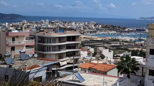 Top down panning shot of a coastal city with a harbor and blue ocean