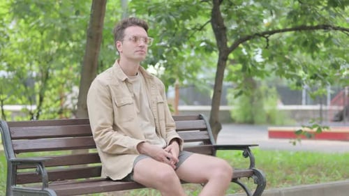 Man on Bench Experiences Back Pain in Park